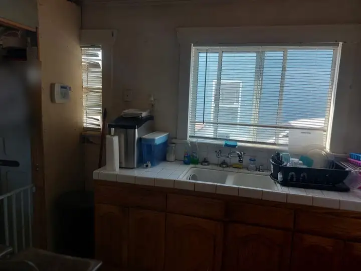 The kitchen: tiled counter, wood cabinets and a window over the sink