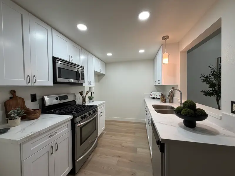 The same kitchen finished for market: white shaker cabinets, stone counters and new flooring
